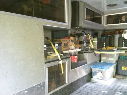 On the left side of the module is a built-in seat, a couple of countertops, and several storage cabinets with sliding glass doors. If you look closely you can see the eye-bolts the author installed so he can strap items in place, and the metal cleat he screwed to the floor to keep the bins on the right from sliding around.