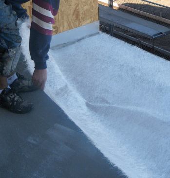 When the first layer of cement has cured, it is covered with overlapping sheets of fiberglass matting.