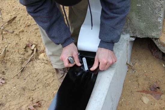After cutting the plastic vapor barrier with a knife, Horgan slips the membrane over the foundation bolt.