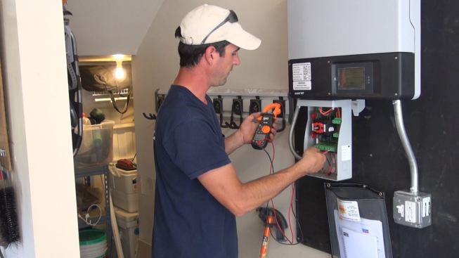 At the inverter disconnect switch in the garage, Bernard measures the DC voltage provided by the panels: 302 volts on string 1, and 305 volts on string 2.