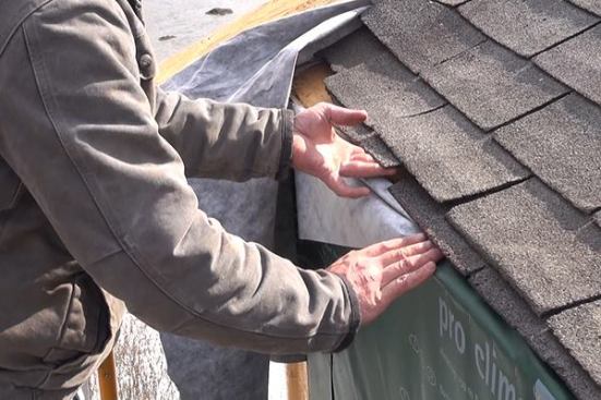 EcoCor job foreman Dan Armstrong tucks ProClima DA membrane under the roof shingles. Later, this joint will be covered with ice and water shield, joining the roof air barrier to the wall’s air-tight vapor control layer at this juncture.
