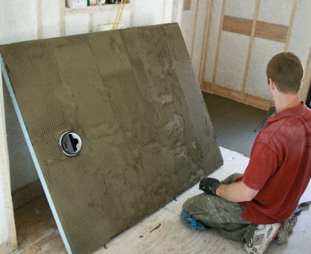 The Wedi shower base has an integral drain with a rubber-flanged fitting that slides into the floor-mounted PVC trap.