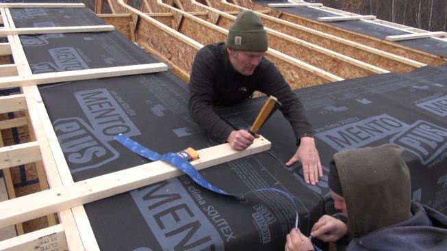 Jesper Kruse staples fabric to the I-joist rafter at the seam. The Mento Plus fabric is not the main drainage plane for this roof assembly (which will be capped with OSB and shingles over an air space). Even so, Kruse installs the fabric air-tight and water-tight.
