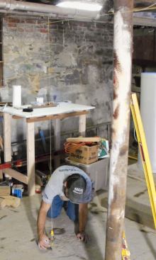 Attaching my Tajima plumb bob to the beam at every mark, I plumb down and lay out the 24-inch-by-24-inch footings.