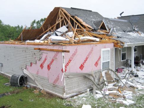 Seen here is the back right corner, where the gable roof over the children's bedrooms was lost. Like most of the homes in the neighborhood, this one was fully sheathed with OSB; pink housewrap and vinyl siding covered the sheathing.