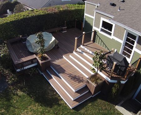 A hedgerow near the side of the deck and the placement of the main deck lower to the ground provide privacy for the owners of this urban Seattle home. Benches and planters complete the sitting area. To minimize maintenance costs, the deck was finished with Fiberon composite decking and stair treads and white Azek cellular PVC risers.