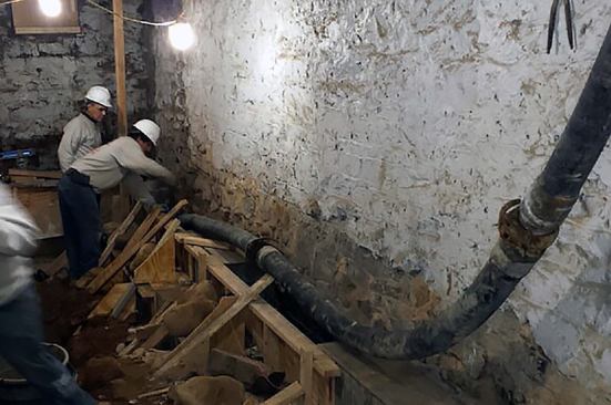 Workers place concrete in the forms for a reinforcing buttress structure in the Brooklyn row house basement.