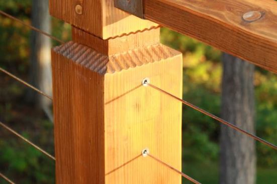 On long runs, cables can pass through intermediate posts without terminations. In the case of wood posts, metal sleeves should be used (pictured) to line the holes drilled through the posts. Otherwise the cables may wear away the wood and increase the amount of sag in the cable.