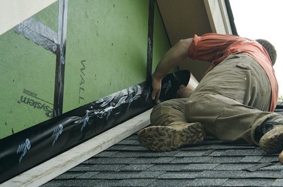 After the step flashing and roofing have been installed, the author tapes flashing to the sidewalls with 6-inch tape.