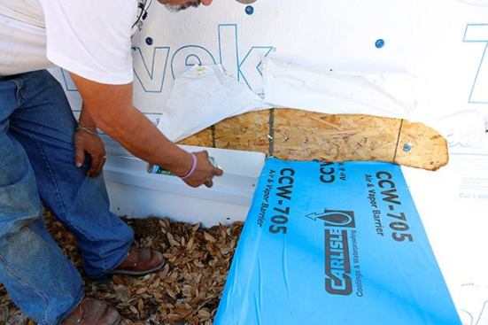 Where the cap meets a wall we again want to run Tyvek Flexwrap. Sam is using High Strength 90 to prime first.