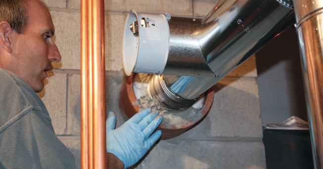 At the base, the author packs the cavity between the new liner and old flue with mineral wool insulation and seals the opening with refractory cement.