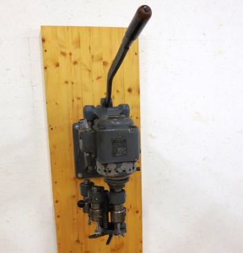 I can’t say for sure what this is; it looks like a drill press with some kind of mechanism for quickly swapping between “chucks” containing different size bits.
