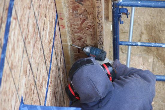 Screwing the I-joist into the wall with a GRK structural fastener.