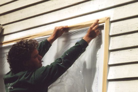 He tucks the plastic underneath before finishing the rest of the siding.