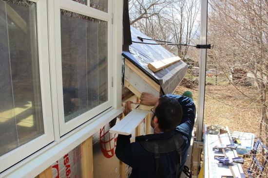 Pollard scribes a cut line onto the soffit board as Fenton holds the other end of the board in place.