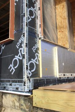 A closer look at the air-tight insulated exterior wall buildout. Grace Ice and Water Shield polyethylene and bituminous membrane wraps over and seals the existing board sheathing. The membrane is sealed to wood window extension bucks using 3M 8067 weather-sealing tape, integrating the window bucks into the air and vapor control layer. Foil-faced polyiso insulation is applied in two layers over the air-tight membrane. The inner layer of rigid insulation is sealed at the seams using Dow Weathermate tape, while the more critical outer layer of rigid insulation (which constitutes the drainage plane behind the wood siding) is sealed with 3M 8067 tape.