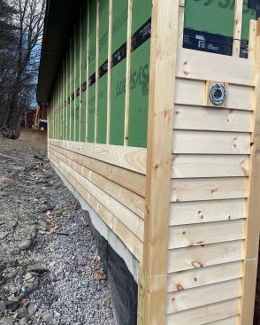 The crew installed full-length clapboards along the back wall to minimize the number of butt joints. They used offcuts for shorter wall sections.