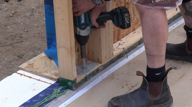 Corson drives an anchor bolt into a pre-drilled hole in the foundation slab.