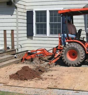Before starting excavation, the author lays down sheets of plywood to protect the paver-stone patio.