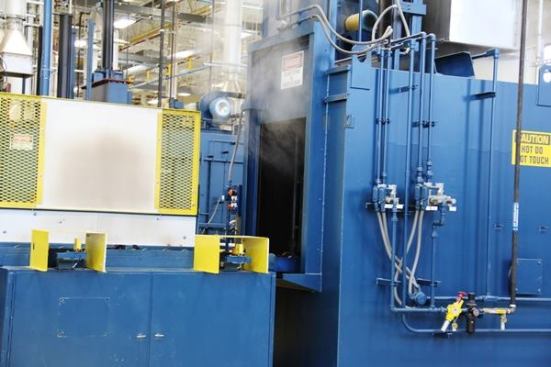 At various points in the heat treating process baskets of parts are run through what is essentially an industrial size dishwasher. The parts are washed in water and detergent to remove contaminants that might react with tool parts when they are in the furnace. What you’re seeing is steam coming out of the open door.