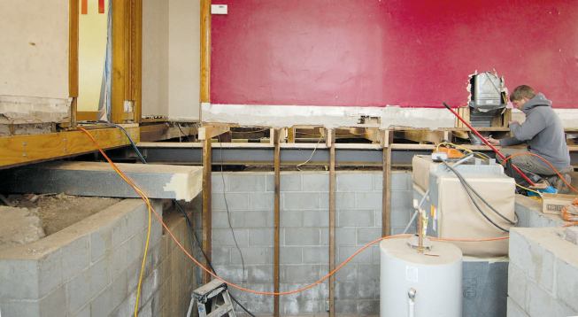 At the center bearing wall, the crew had to work around the temporary supports under the short joist remnants as the steel was inserted.