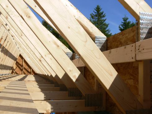 A closer view of the raised heel detail on the trusses shows the 2x4 bracing applied to the inboard side of the truss tail, and the wall system’s OSB skin (which extends up to cover the truss heels).