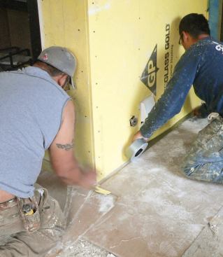 Before applying the WeatherSeal elastomeric waterproofing membrane, workers use plywood and duct tape to prevent the coating from dripping onto a concrete porch floor.