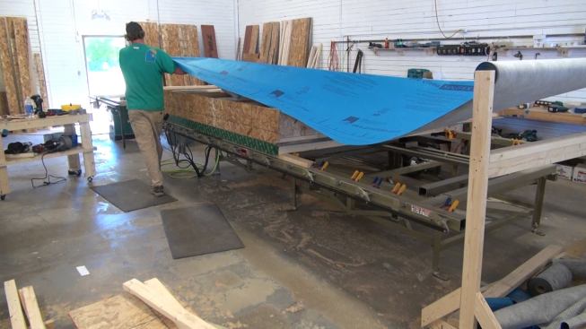 Rolling out ProClima Solitex Mento fabric over the wood I-joist outer section of the wall panel. Air-tight but highly vapor-permeable, the Mento fabric provides a weather barrier and serves to contain the cellulose insulation within the I-joist cavity while allowing the wall to dry in the outboard direction.