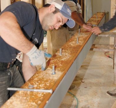 To prevent possible conflicts between bolt and joist layouts, they drilled recesses for the nuts and washers using a 2-inch spade bit, then installed the bolts.