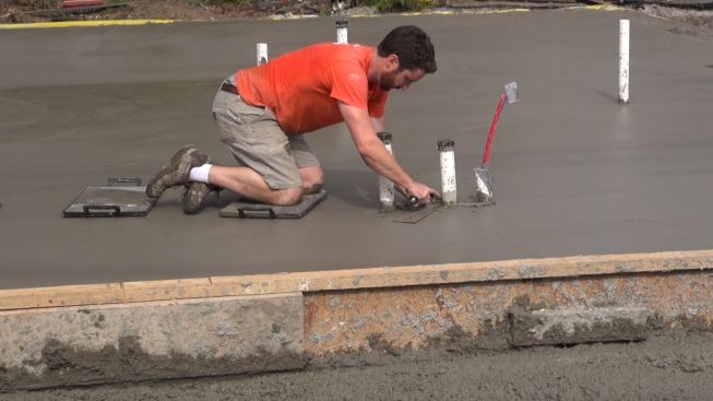 A few small parts of the slab couldn’t be reached by the long screed made of wood I-joists. Here, Evan Smith trowels a small area between two plumbing pipes.