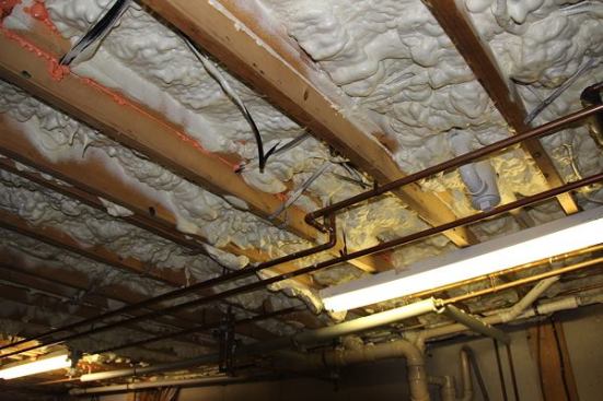 Isolating the basement from the home's living space with spray foam was less costly than insulating the basement. Given the decades' accumulated wiring, pipes, and other tangled mechanicals, the air seal between floors is good — but not perfect.