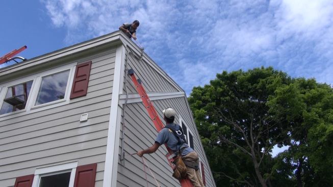 With the outdoor portion of the conduit run fully assembled, Janarelli and Bernard pull a 50-foot run of wire through the conduit—enough to reach from the rooftop solar array to the inverter inside the garage. The bundle of wires includes two sets of conductors (one for each string of panels), along with a heavy bare copper grounding cable that must be bonded to every mounting bracket on the roof.
