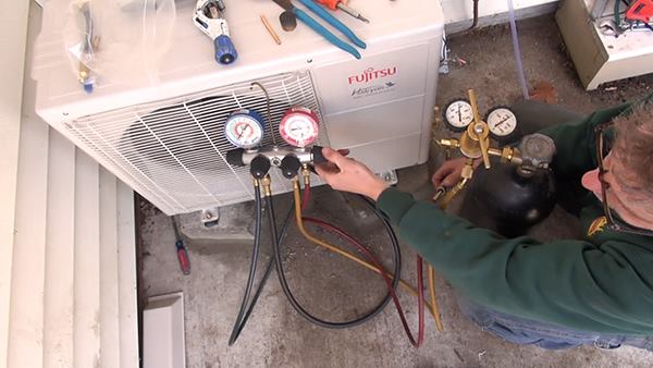 Dave Ragsdale charges the refrigerant tubing for the mini-split system with 600 pounds of compressed nitrogen. The crew will leave the system pressurized with nitrogen overnight to test for leaks before charging the system with refrigerant the next day.