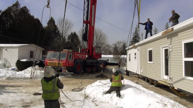 Crew members connect the modular unit to its lifting cables in preparation for setting the house.
