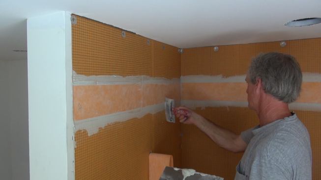 Boucher likes to use a five-inch spackle knife, with the corners filed off to prevent gouging, to smooth down the Kerdi-Band membrane and remove excess mortar squeeze-out.