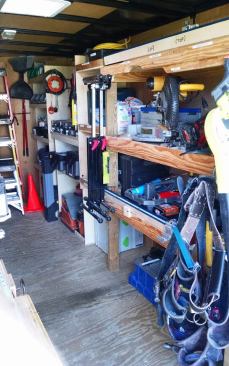 The right side of the trailer contains deep shelving. Heavy items, such as the miter saw, are stored high so there’s no bending over to lift them. Note the 
Kreg Foreman on the floor, just ahead of the hanging tool belts.