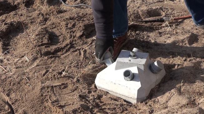 The installer sets rubber caps over the steel pins by hand. At this point, the caps can be removed so an inspector can verify the pin depth, but after the inspection, the caps will be tapped down and the joint sealed with adhesive sealant.