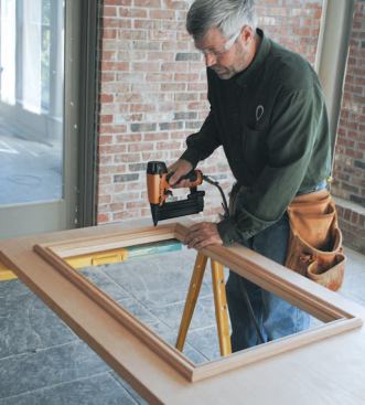 The assembly is used for reference as he flips the door over and glues and pins the remaining frame to the door. The tacked frame will be removed and finish-coated along with the rest of the door before the glass is installed.