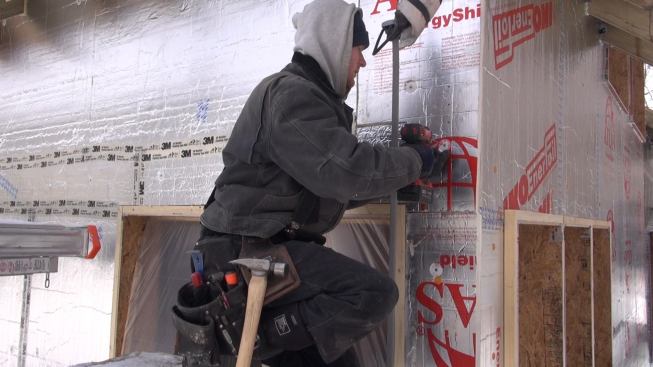 Mitchell attaches the sheet of foam with a long screw and washer.