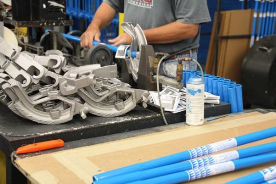 This worker is assembling 3/4-inch conduit benders; the wheels on the assembly device spin the handle so it threads into the head.