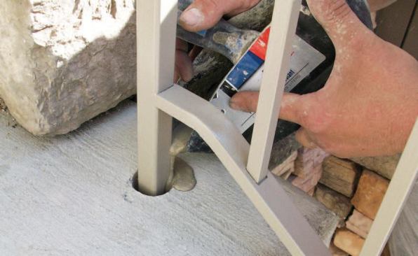 After dry-fitting the railing and checking for level and plumb, the installer mixed up a small batch of Super Flow-Rock, a rapid-setting nonmetallic hydraulic cement designed for anchoring metal to concrete. He poured it into the holes, allowed it to set up for about 20 minutes, then cleaned it up with a trowel.