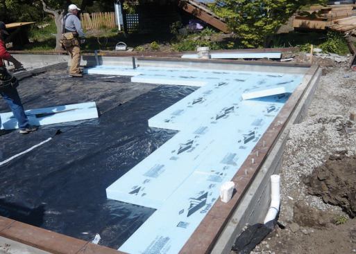 The stone base inside the stem wall was leveled and compacted, then covered with 6-mil poly and 4-inch XPS insulation.
