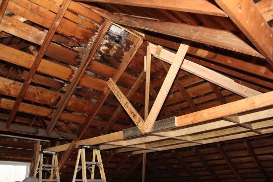 With the ridge and hips jacked into position, the crew site-built a pair of structural trusses spanning the house, using engineered lumber. The ends of the trusses rest on full-height LVL posts that bear directly on the foundation. The site-built engineered trusses are the backbone of a new structural system, serving to support the ridge and hip members at the apex of the roof frame.