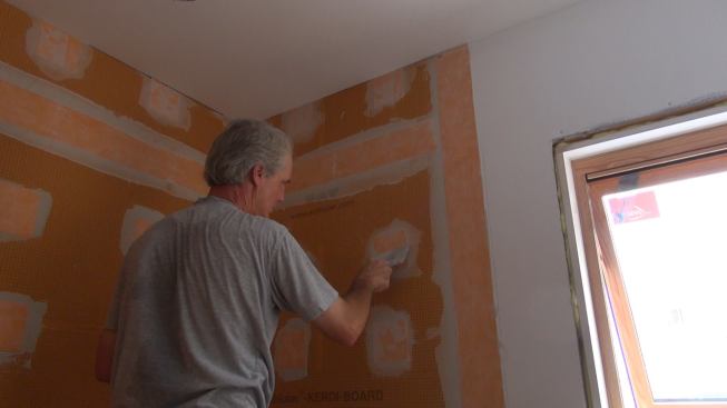 Boucher works a Kerdi-Band patch into the mortar to ensure a good bond. Once the mortar has cured overnight, the shower wall will be effectively waterproofed and ready for tiling.