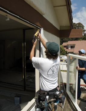 An installer applies sealant around the face of a window opening before setting the replacement window.