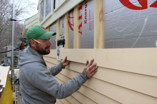 Fenton “dry fits” a clapboard. He will prime the end cut, then slip a square of asphalt paper behind the joint for secondary weather protection before pinning the end of the clapboard in place.