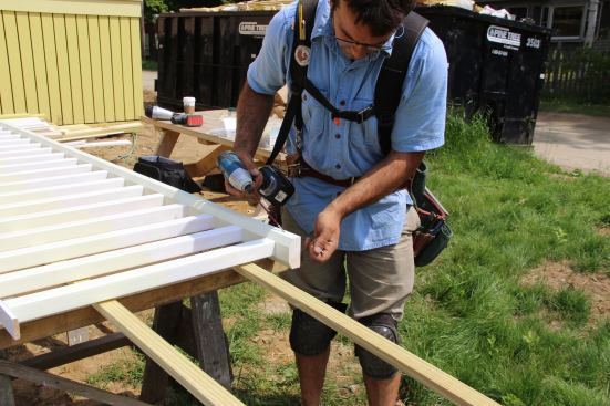 Pollard pre-sets #8 three-inch screws in the bottom rail as he gets ready to install the baluster and rail section between the porch columns.