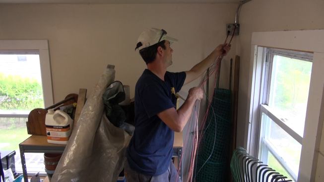 Inside the garage, project manager Brandon Bernard pulls the conductors through the wall as Janarelli feeds them in from the outside.