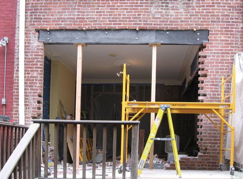 Temporary supports help stabilize the header while the remaining brick is removed.