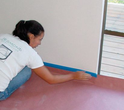 The first step in protecting an existing floor is to lay out the rosin-paper border at the edges of the room. Making a sharp crease where the paper meets the wall allows it to sit flat and reduces the risk of tearing when the floor is swept and vacuumed.